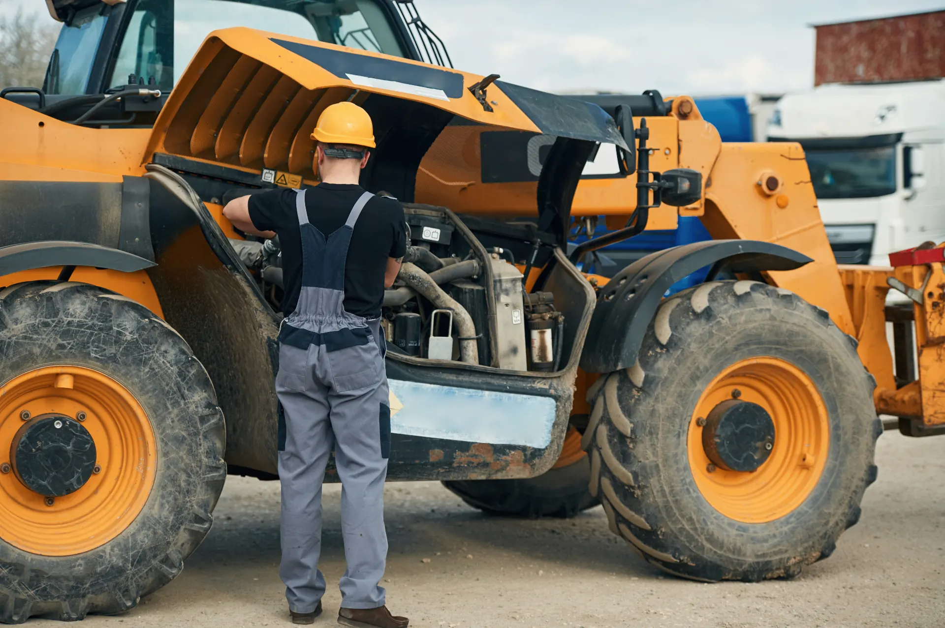 A mechanic working on the engine of a telehandler